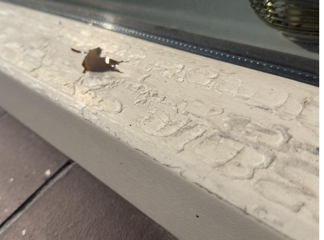Close-up van verweerde, beschadigde folie op een kozijn